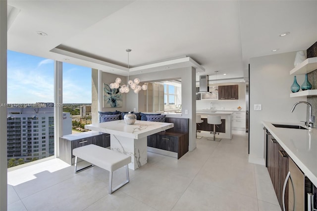 dining room with light tile patterned flooring, recessed lighting, an inviting chandelier, and a tray ceiling