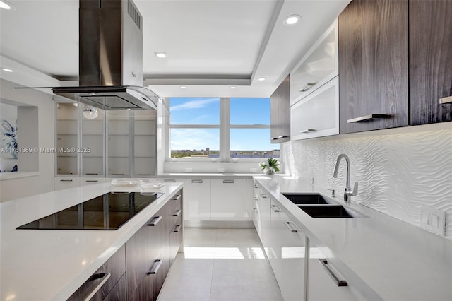 kitchen with modern cabinets, black electric cooktop, island exhaust hood, and a sink