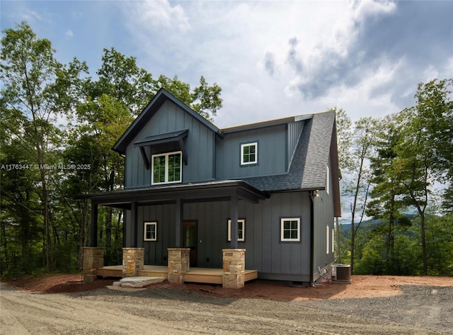 view of front of house with central air condition unit, covered porch, board and batten siding, and a shingled roof