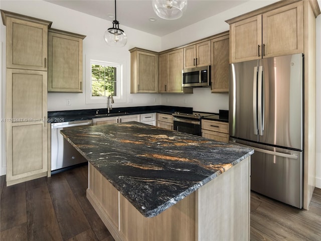 kitchen featuring dark stone countertops, dark wood-style flooring, appliances with stainless steel finishes, and a sink