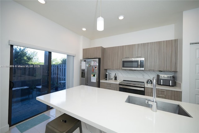 kitchen with a sink, stainless steel appliances, light countertops, and modern cabinets