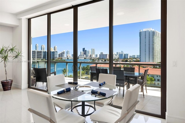 dining room featuring light tile patterned floors, expansive windows, a city view, and a healthy amount of sunlight