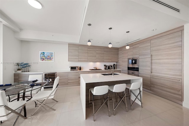 kitchen featuring light countertops, a kitchen breakfast bar, light tile patterned flooring, modern cabinets, and a sink