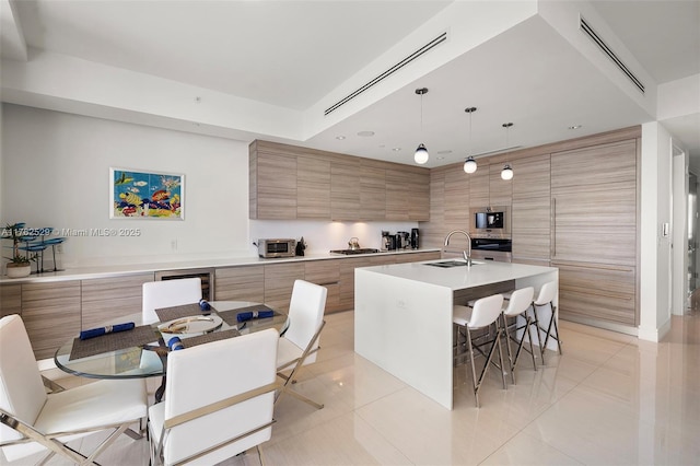 kitchen with a sink, a kitchen breakfast bar, modern cabinets, and brown cabinetry