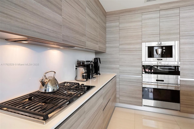 kitchen featuring light tile patterned flooring, appliances with stainless steel finishes, modern cabinets, and light countertops