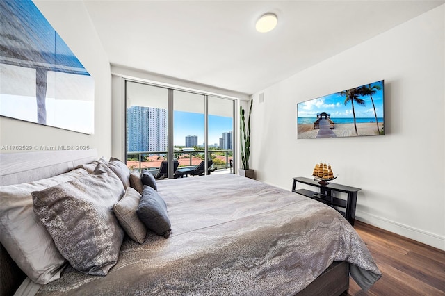 bedroom featuring baseboards, floor to ceiling windows, wood finished floors, a view of city, and access to outside