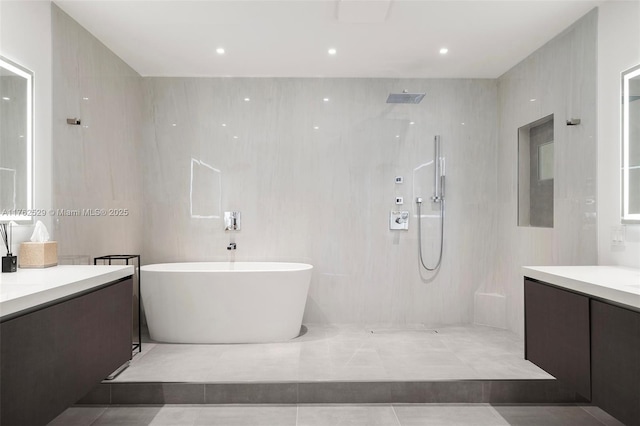 bathroom featuring tile walls, walk in shower, a freestanding bath, recessed lighting, and vanity