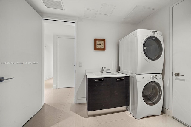 clothes washing area with visible vents, attic access, stacked washer and dryer, light tile patterned floors, and a sink