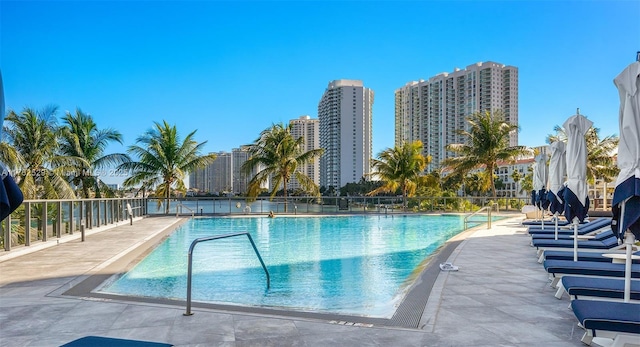 community pool with a city view, a patio area, and fence