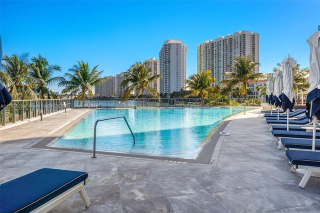 pool featuring a city view, a patio, and fence