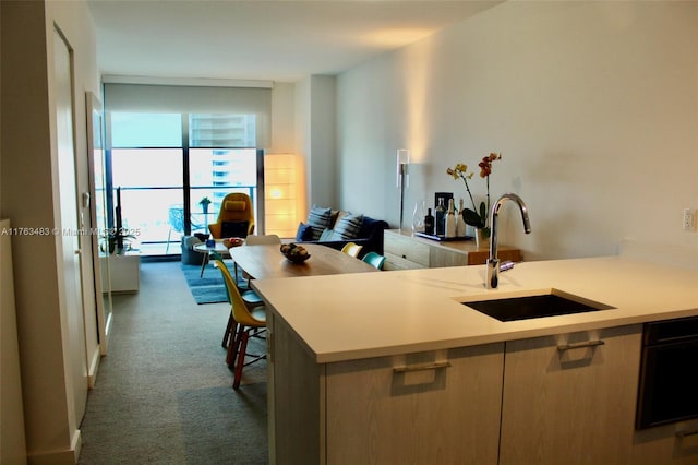 kitchen with a sink, open floor plan, dark carpet, floor to ceiling windows, and light countertops