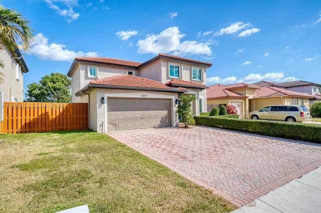 mediterranean / spanish house featuring fence, a tile roof, a front yard, stucco siding, and decorative driveway