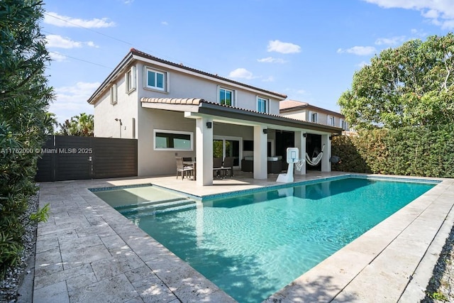 rear view of house with a fenced in pool, stucco siding, a patio, and fence