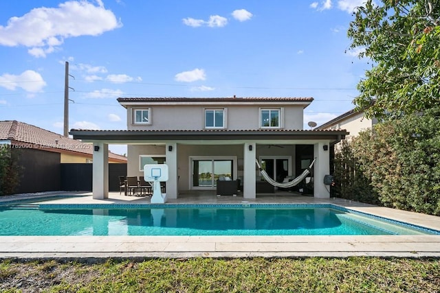 back of property with a patio area, stucco siding, an outdoor pool, and a tile roof