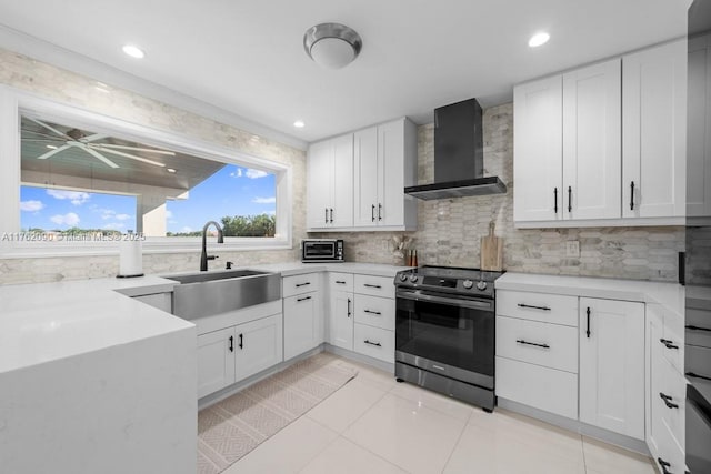 kitchen with stainless steel electric range oven, wall chimney range hood, tasteful backsplash, and a sink