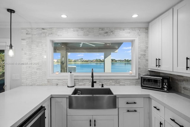 kitchen with a wealth of natural light, a toaster, a water view, and a sink