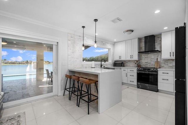 kitchen featuring a breakfast bar area, visible vents, a sink, black appliances, and wall chimney exhaust hood