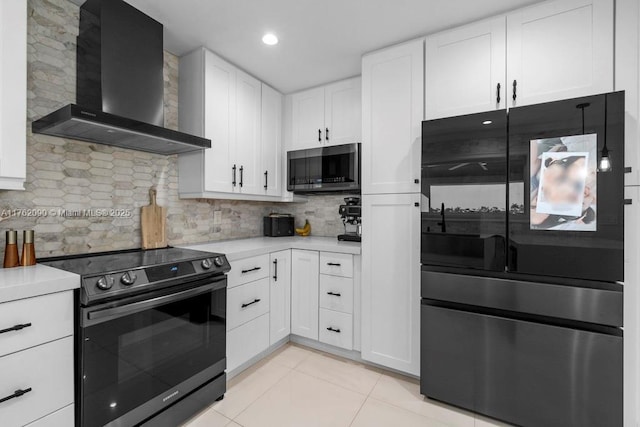 kitchen featuring appliances with stainless steel finishes, white cabinets, wall chimney exhaust hood, light tile patterned flooring, and light countertops