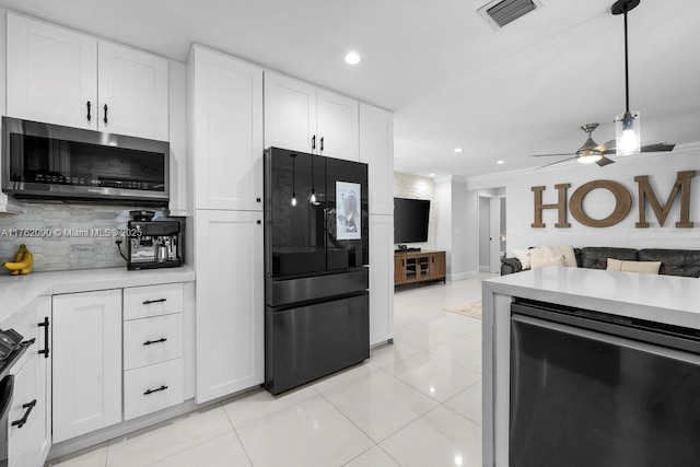 kitchen featuring visible vents, stainless steel microwave, freestanding refrigerator, light countertops, and decorative backsplash