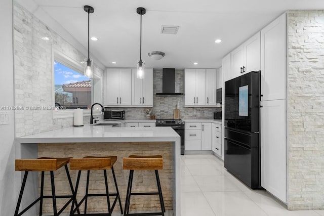 kitchen with black appliances, a kitchen breakfast bar, backsplash, a peninsula, and wall chimney exhaust hood