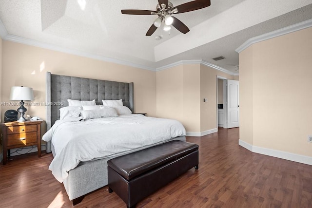 bedroom with visible vents, ornamental molding, a tray ceiling, wood finished floors, and baseboards