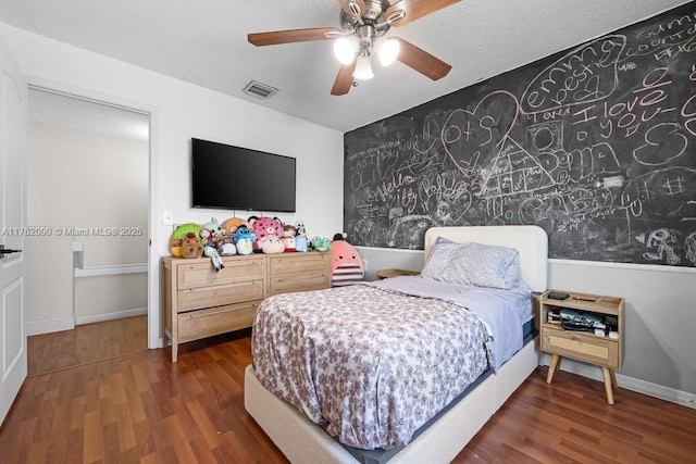 bedroom featuring visible vents, baseboards, a textured ceiling, and wood finished floors