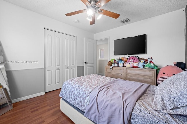 bedroom with a closet, visible vents, a textured ceiling, and wood finished floors