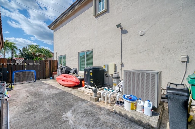 view of property exterior with a patio, central AC unit, fence, and stucco siding