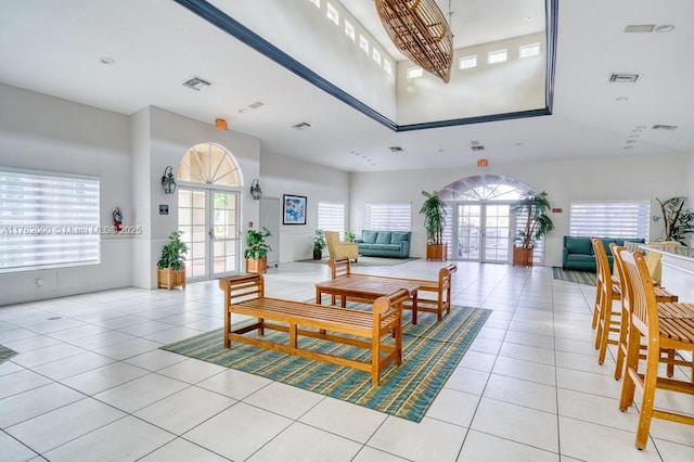 dining area with light tile patterned floors, french doors, visible vents, and a towering ceiling