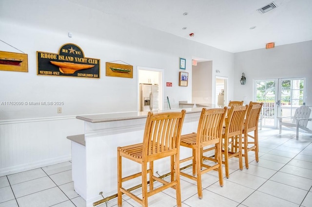 dining area with light tile patterned flooring, visible vents, and a wainscoted wall