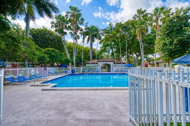 community pool with a patio and fence