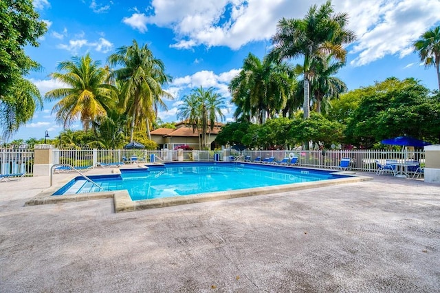 community pool with a patio and fence