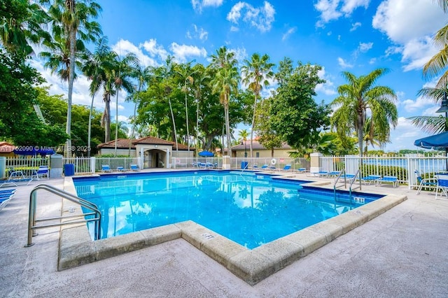 pool with a patio area and fence