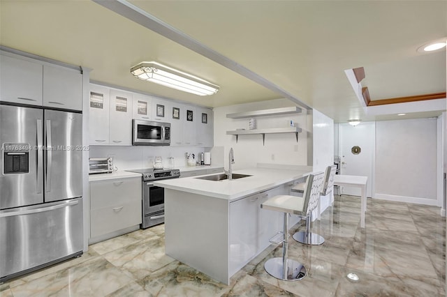 kitchen featuring a breakfast bar, a peninsula, open shelves, a sink, and appliances with stainless steel finishes