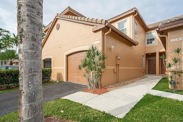 view of front facade with aphalt driveway, stucco siding, an attached garage, and a tiled roof