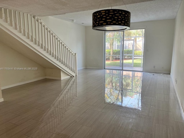 spare room with wood tiled floor, baseboards, and a textured ceiling