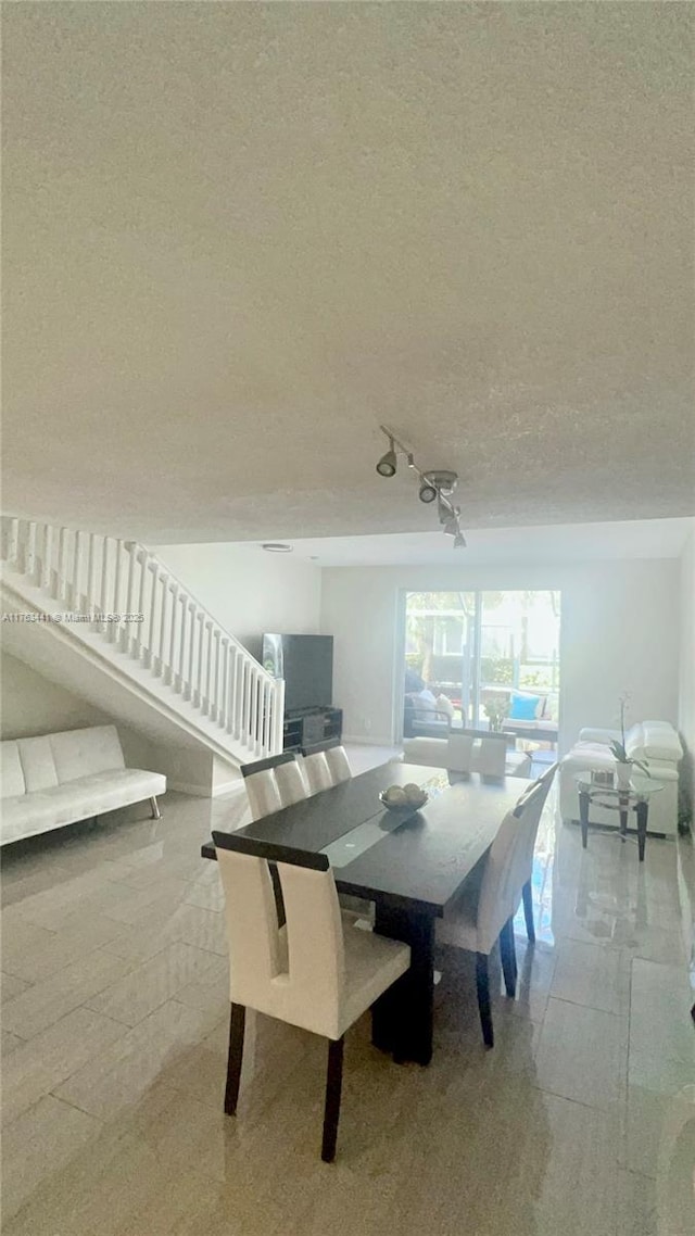 dining room featuring a textured ceiling and stairs