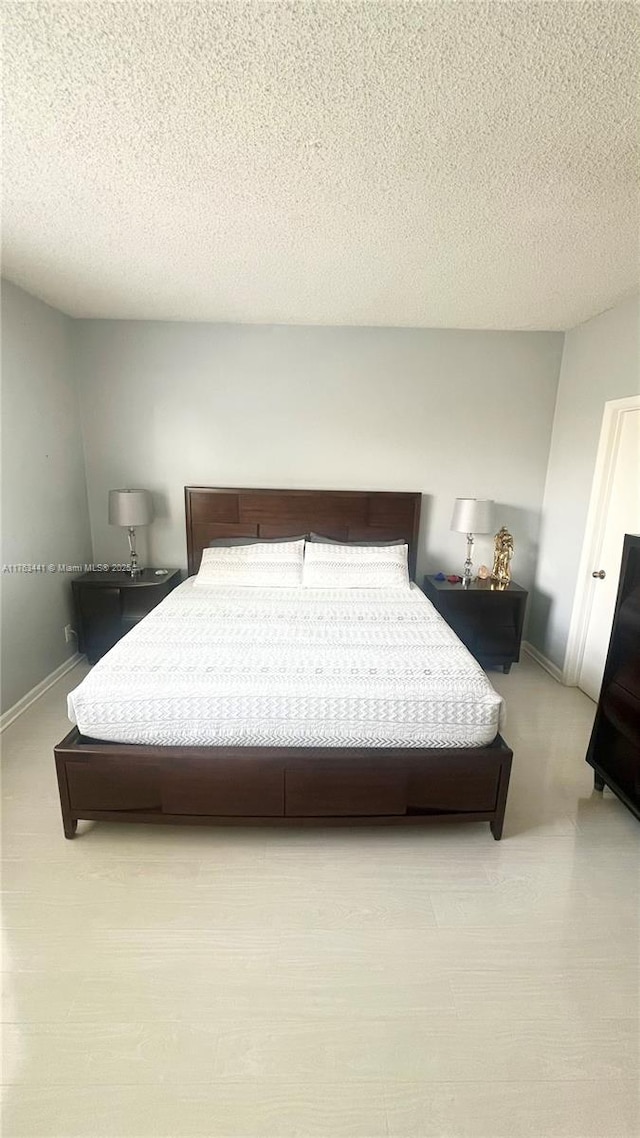 bedroom featuring a textured ceiling and baseboards