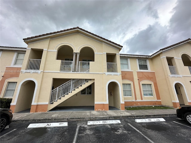 view of property with stairs and uncovered parking