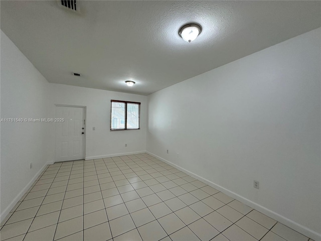 spare room with baseboards, visible vents, and a textured ceiling