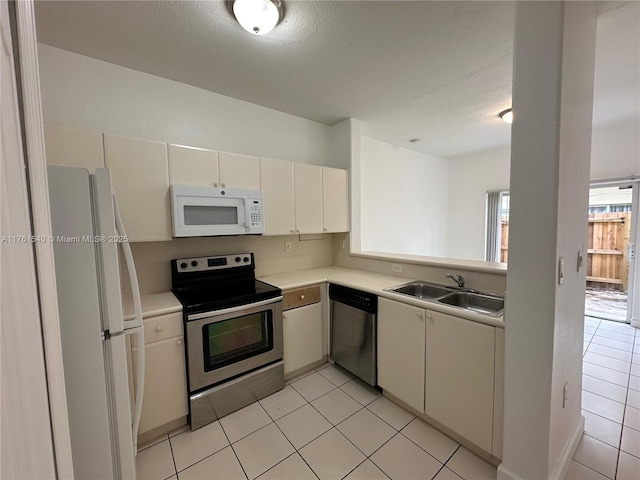 kitchen with light tile patterned flooring, appliances with stainless steel finishes, light countertops, and a sink