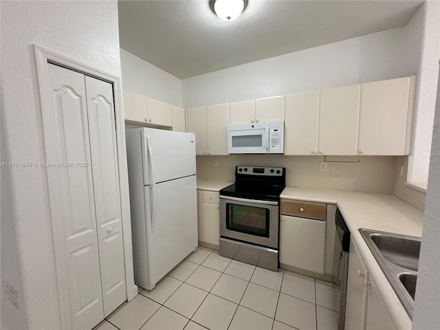 kitchen with a sink, white appliances, light tile patterned flooring, and light countertops