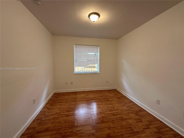 empty room featuring baseboards, a textured ceiling, and wood finished floors