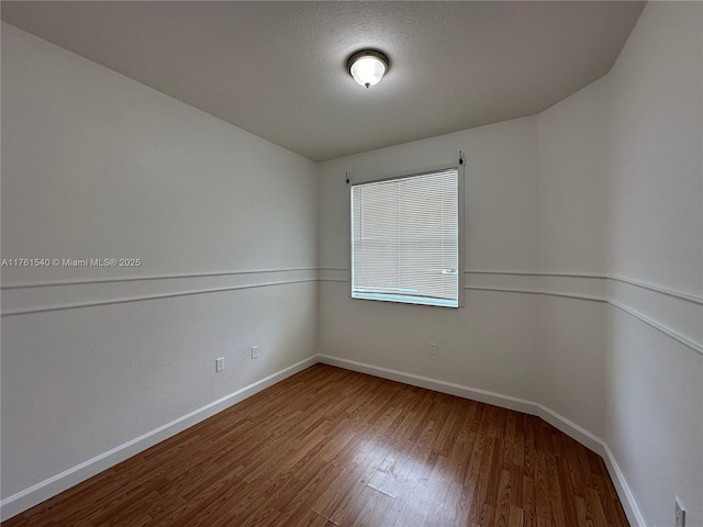 unfurnished room featuring wood finished floors, baseboards, and a textured ceiling