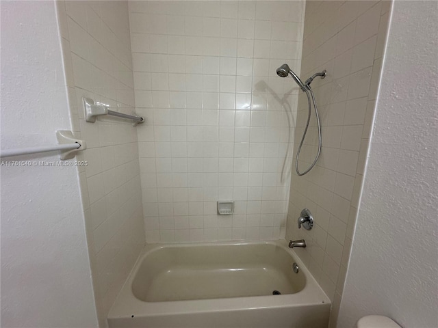 full bath with shower / bath combination and a textured wall