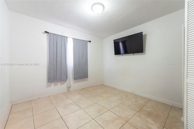 empty room with tile patterned flooring and baseboards