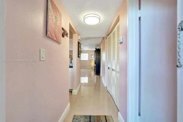 hall featuring light tile patterned floors and baseboards