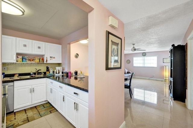 kitchen with a sink, open floor plan, ceiling fan, and white cabinetry