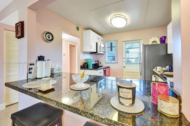 kitchen with visible vents, white cabinets, appliances with stainless steel finishes, and dark stone counters