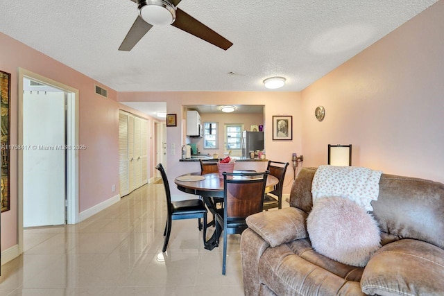 dining area featuring light tile patterned floors, a ceiling fan, baseboards, visible vents, and a textured ceiling